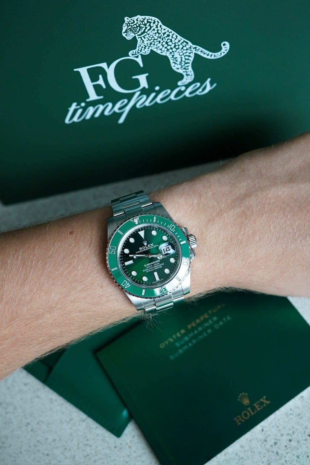 A watch on the wrist, resting on the FG timepieces boxes